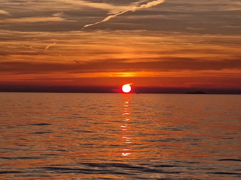A red sun touching the sea horizon under an orange sky